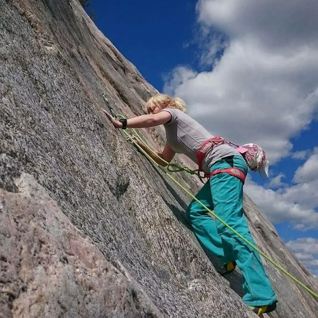 Nainen kiipeilee kallion seinämällä Nalkkilan släbillä.