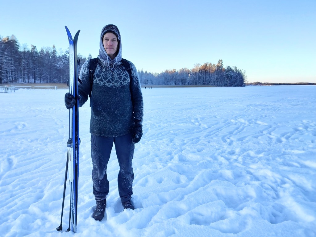Mies villavaatteissa lähdössä hiihtämään.