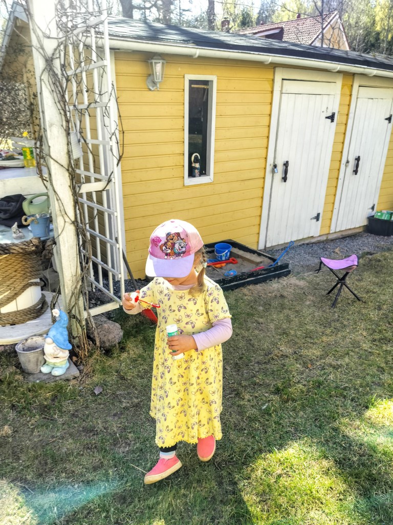 Lapsi puhaltaa saippuakuplia keltaisen vajan edessä.