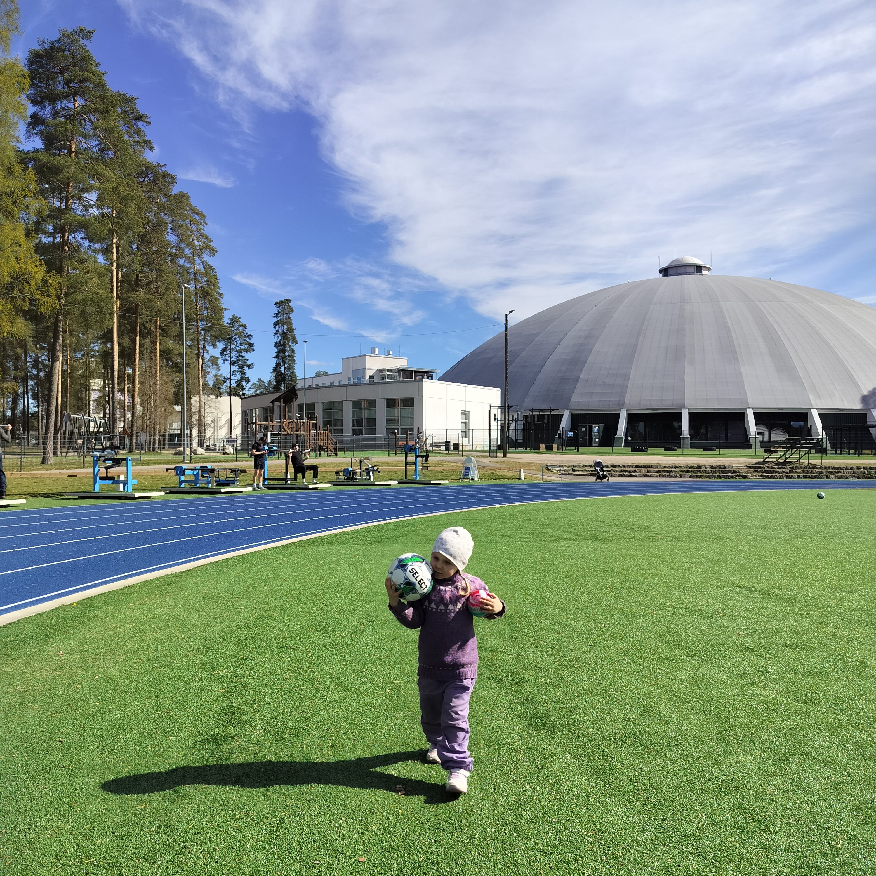 Lapsi kantaa jalkapalloa tekonurmikentällä