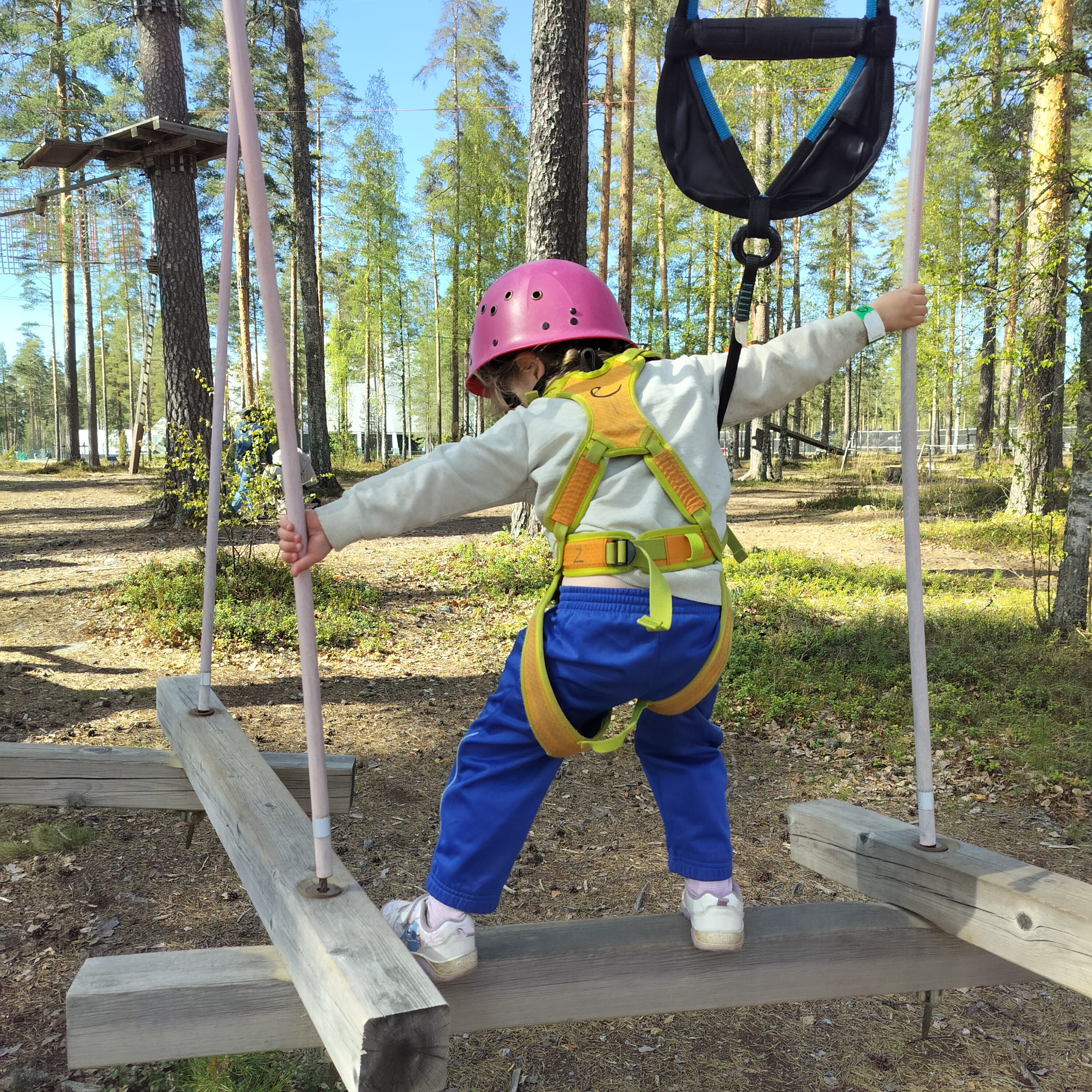 Lapsi tasapainottelee pölkkyjen päällä seikkailupuistossa.