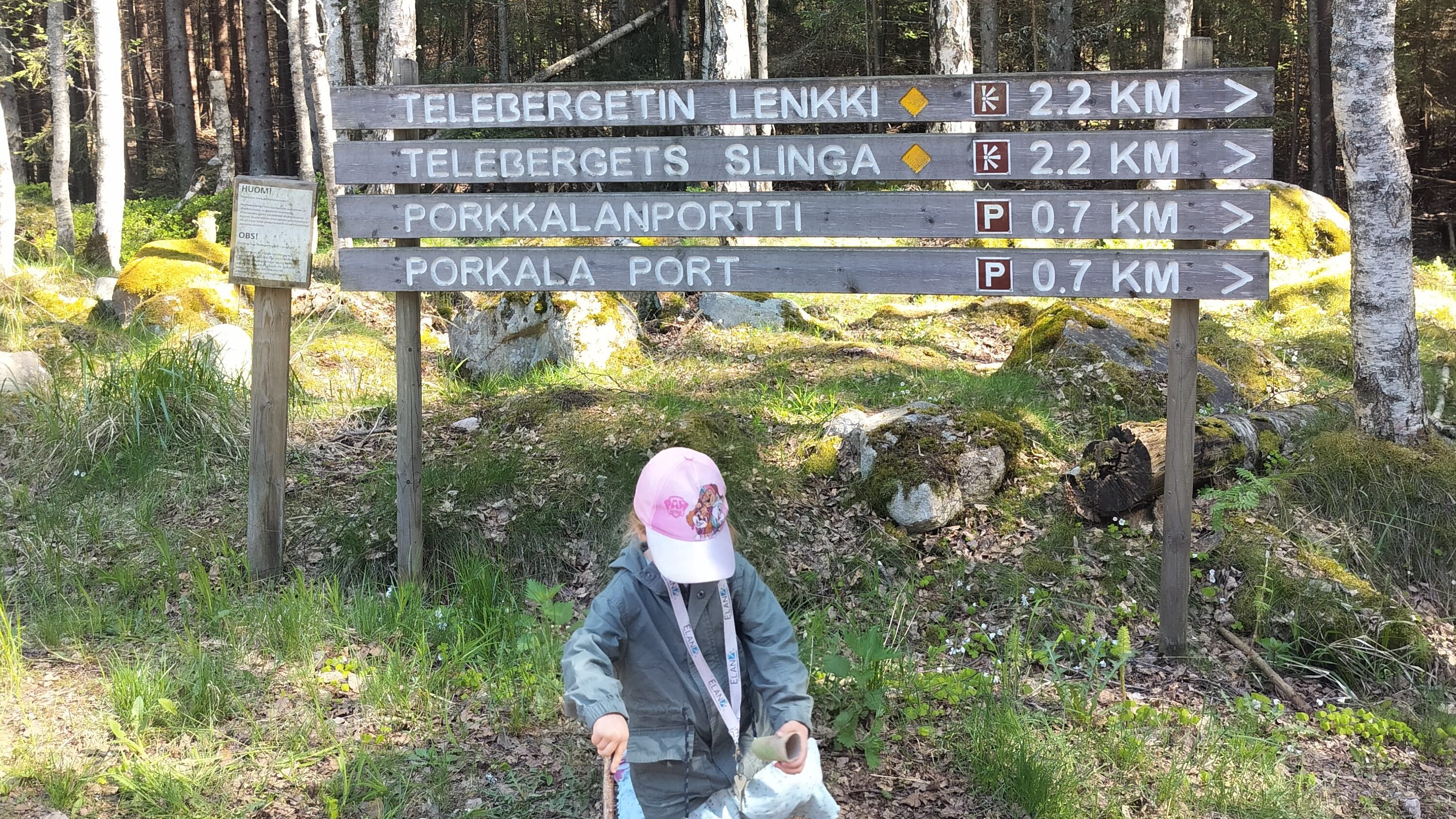 Pieni lapsi istuu retkeilyreitin kyltin edessä. 