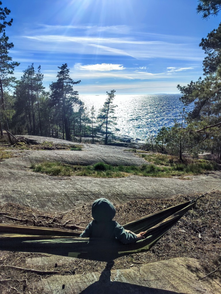 Pieni lapsi riippumatossa kauniin merimaiseman edessä. 