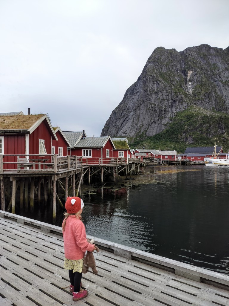 Reine kalastajakylän punaiset rorbu -mökit ja satama vuorimaiseman edessä.